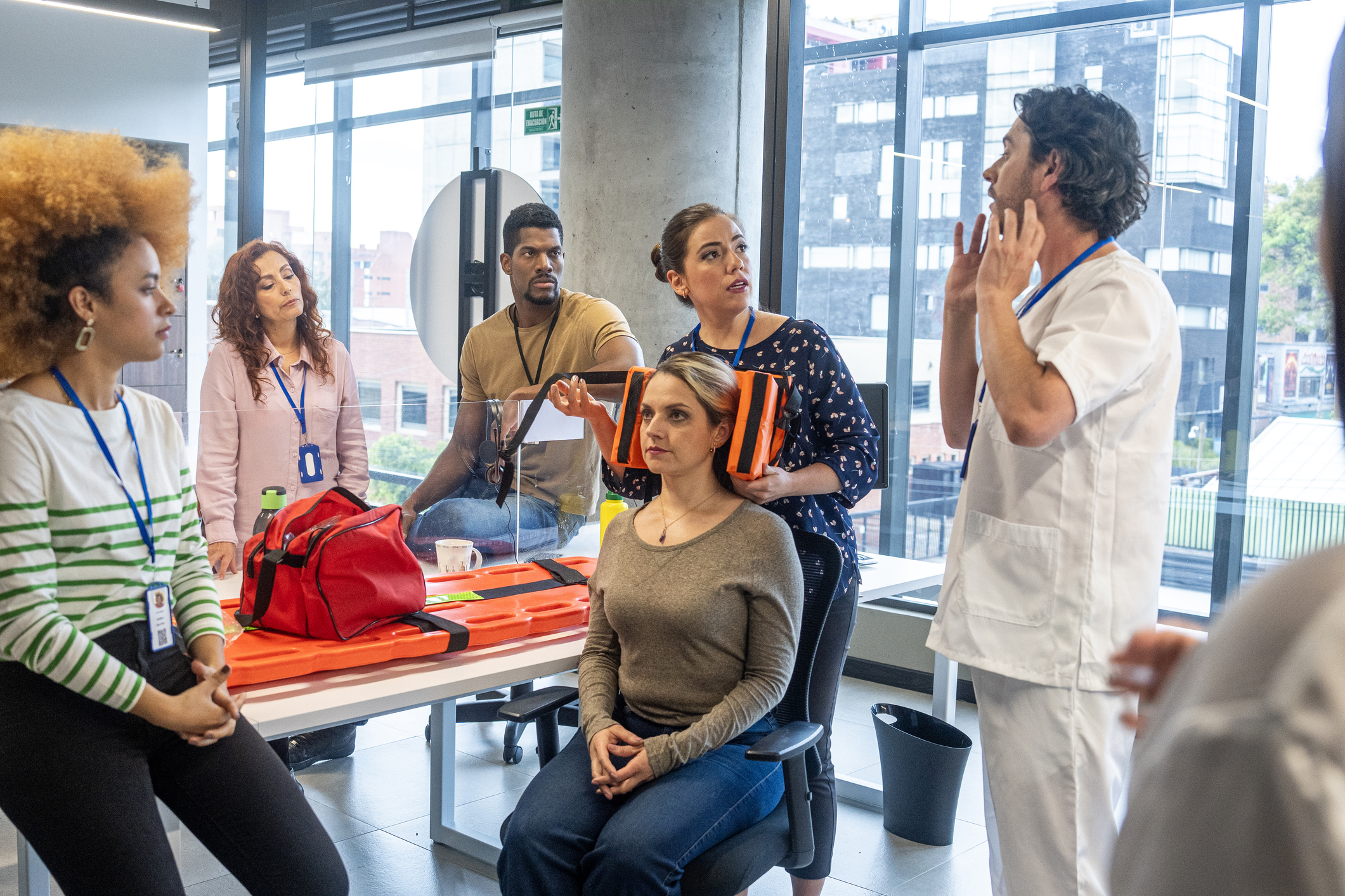 Ein Erste-Hilfe-Ausbilder erklärt einer Gruppe von Angestellten Erste-Hilfe-Maßnahmen.