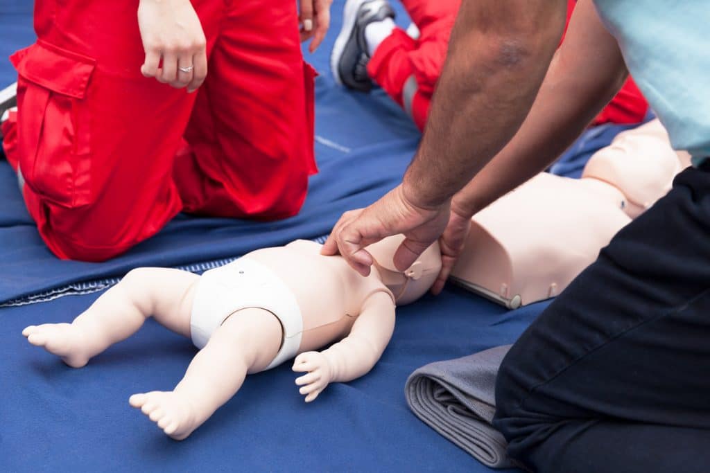 Eine Person übt an einer Babypuppe die Wiederbelebung.