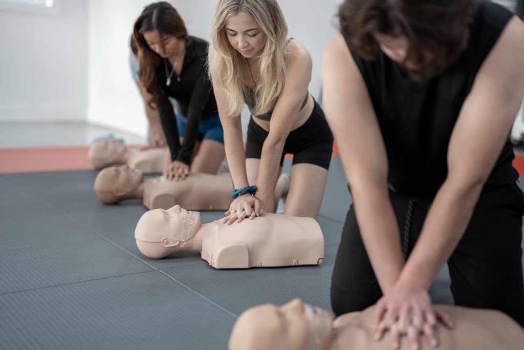 Mehrere Personen, die HLW in einer Erste-Hilfe-Schulung üben.